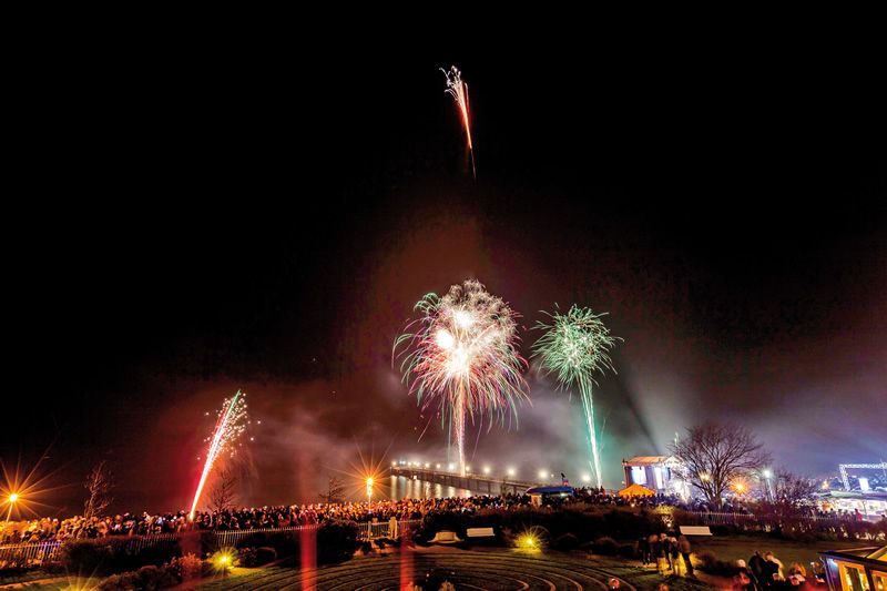 Neujahrsfeuerwerk an der Brücke Nachtaufnahme eines Feuerwerks über einer Menschenmenge an einer beleuchteten Brücke.
