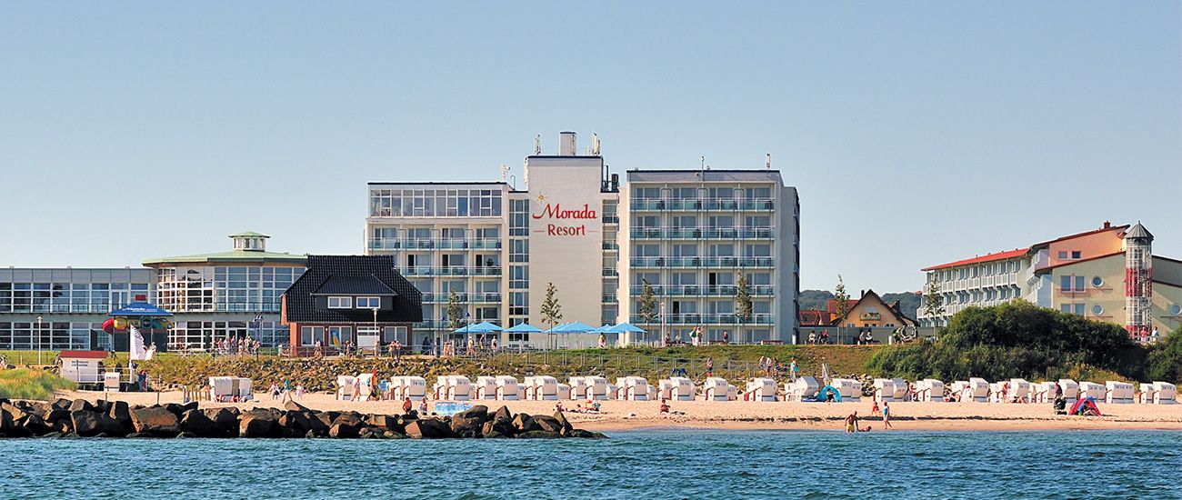 Strandhotel mit direkter Lage am Meer Hotelanlage am Strand mit Liegestühlen und Sonnenschirmen